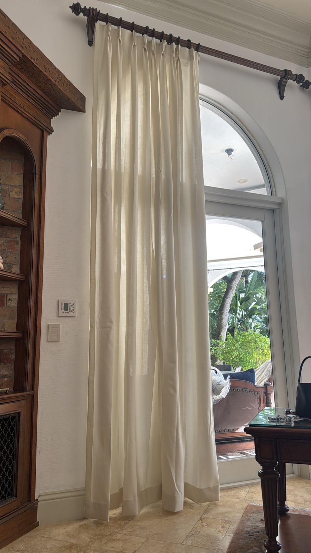 Made-to-measure ivory drapery on a tall arched window in Miami