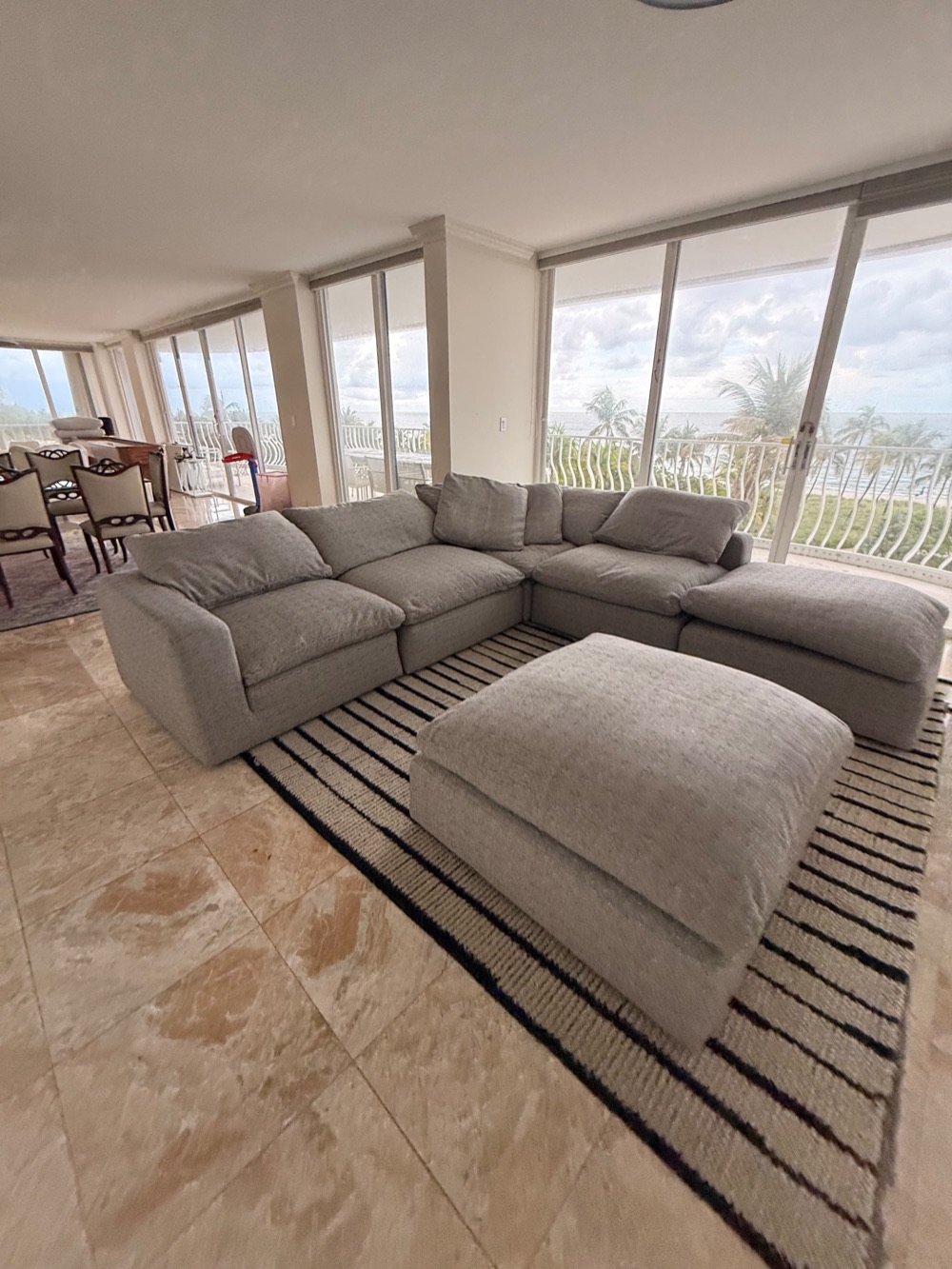 Custom grey sectional and ottoman in an oceanfront Miami living room